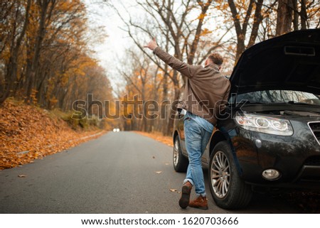 Man after a car breakdown at the side of the road. A man tries to stop a car for help.