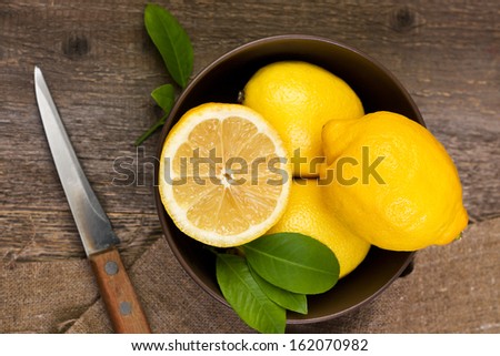 lemons in a bowl on wooden background Royalty-Free Stock Photo #162070982