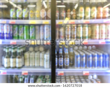 Defocused blurred background, grocery store: Refrigerator full of beer. Beer in glass and aluminum cans in the store.