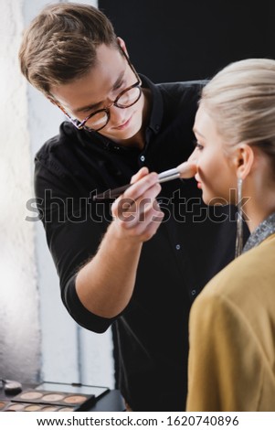 selective focus of Makeup Artist doing makeup to model on backstage