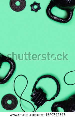 Sports picture. Kettlebells, dumbbells and headphones mint green background. Flat lay, top view, copy space.