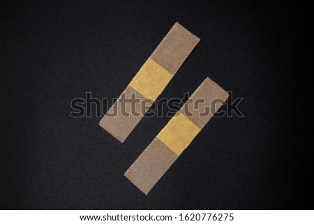 Two Adhesive bandages against a black background. Medical adhesive bandages stock image. Image of medical plasters glued in a line