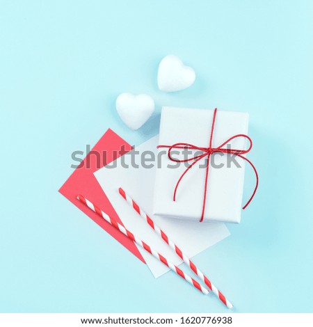 Valentine's Day, Mother's day art design concept for promotion - Red, white wrapped gift box isolated on pastel light blue color background, flat lay, top view.