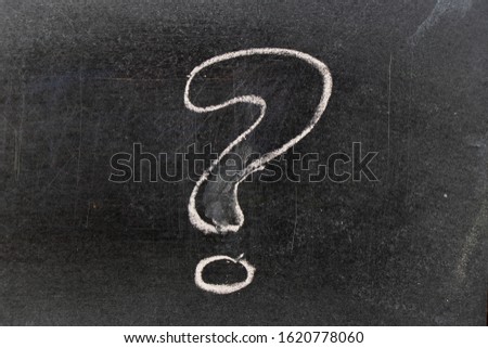 White color chalk hand drawing in question mark shape on blackboard background