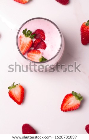 glass with yogurt and fresh raspberries and strawberries on white