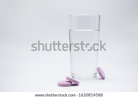 Transparent glass glass with clean water, next to which are soluble. instant or dissolve pink tablets vitamin C, dietary supplements, painkillers