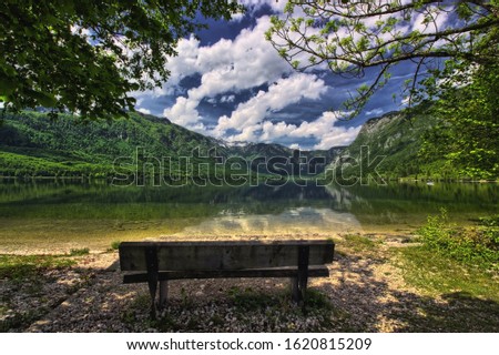 Colorful spring photo of the Bohinj Lake, Triglav National Park, Julian Alps, Slovenia.  Empty bench in the foreground. Artistic style post processed photo.