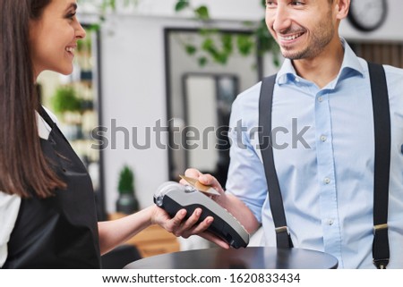 Pleased customer paying by credit card in hair salon 