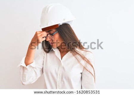 Young beautiful architect woman wearing helmet and glasses over isolated white background tired rubbing nose and eyes feeling fatigue and headache. Stress and frustration concept.
