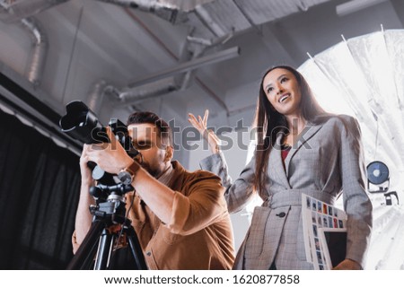 low angle view of photographer taking photo and producer smiling on backstage