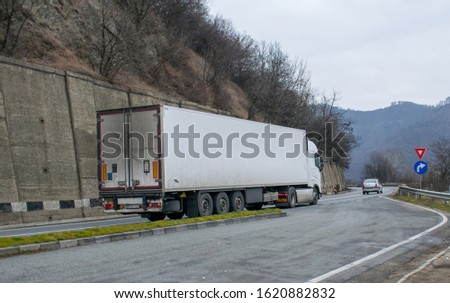 Freight transport truck in traffic. Traffic signs on the roadside. NO logo or brand.