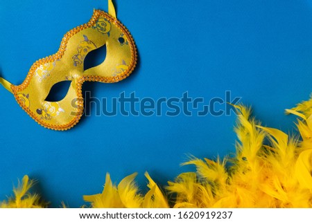 Yellow mask and feather boa, cape, carnival costume, on a blue background