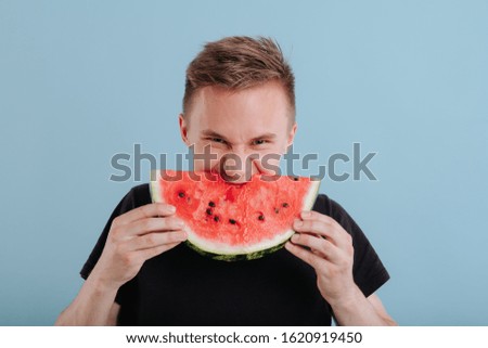boy eats watermelon, in studio, isolated on blue background, copy space