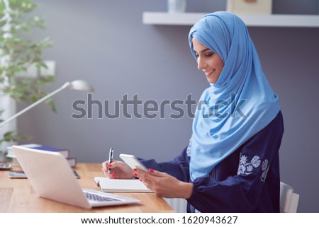 Muslim adult woman using smartphone