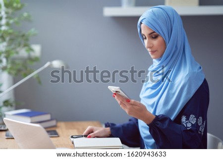 Muslim adult woman using smartphone