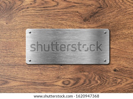 Blank polished silver plate on wooden background to ad text, names or logos Royalty-Free Stock Photo #1620947368