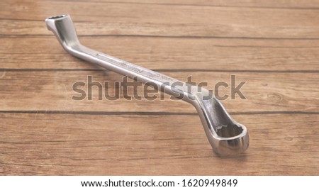 old silver metal wrench on a wooden background, macro, soft focus