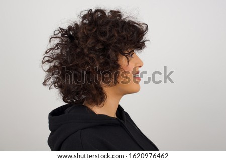 Profile of smiling woman with healthy pure skin, has contemplative expression, ready to have outdoor walk, isolated over white studio wall with copy space