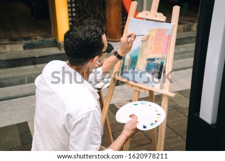 Young man painting on canvas.