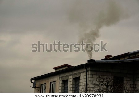 black smoke comes from chimney of a house against gray sky, heating with coal in winter. environmental problem of smog in Beskid Mountains, Zywiec, Krakow. heating system needs to be Royalty-Free Stock Photo #1620978931