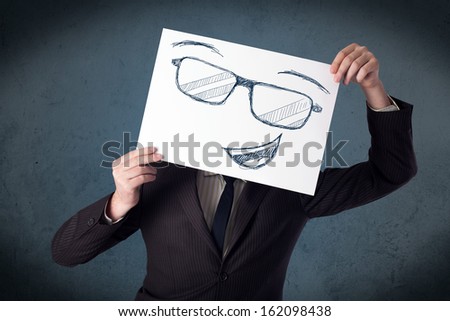 Young businessman holding a paper with smiley face in front of his head