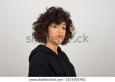 Beautiful woman with snobbish expression curving lips and raising eyebrows, looking with doubtful and skeptical expression, suspect and doubt. Standing indoors over gray background. Royalty-Free Stock Photo #1621001401