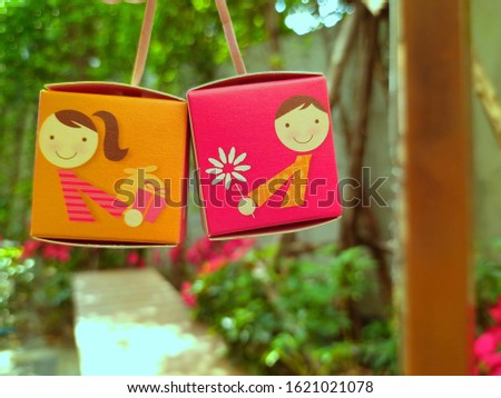 Picture of a cartoon girl on the mini paper box which she is giving a present and picture of a cartoon boy on the mini paper box which he is giving a flower
