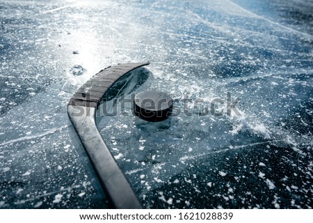 Details close up hockey puck on a frozen pond. Ice skating in nature at sunset in winter. Travel and sports