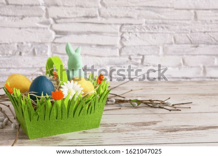 Colorful Easter eggs and Easter bunny in a green basket. Easter background. Happy Easter time. Copy space.