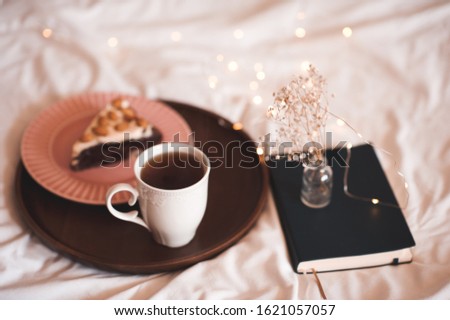 Tasty breakfast with cup of balck tea and piece of pie in bed closeup. Good morning. 
