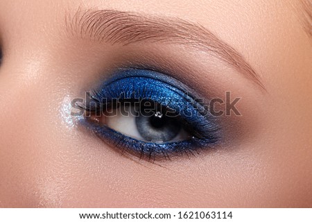 Closeup Macro of Woman Face with Blue Eyes Make-up. Fashion Celebrate Makeup, Glowy Clean Skin, perfect Shapes of Brows. Shiny Shimmer Royalty-Free Stock Photo #1621063114