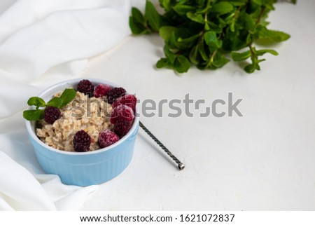 Breakfast consisting of oatmeal, nuts and fruits. Kiwi raspberries blackberries pomegranates almonds mint decorate a plate. Healthy eating,