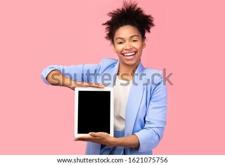 Presenting New Product. Beautiful black girl holding tablet with blank black screen. Mock up, copyspace, pink wall