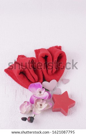 Valentine's day concept. Spa for lovers. two red towels folded in the form of hearts, pink orchid and curly soap on white towel background.