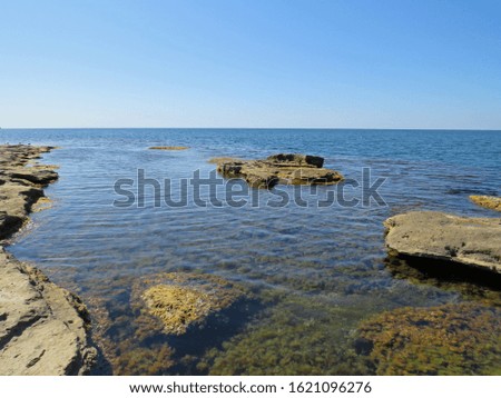 Beautiful sea landscape. Endless sea on a Sunny summer day. Large stones and rocks on the background of the sea and blue cloudless sky.
