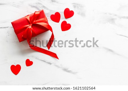 Valentine's Day. Red box with a bow and red hearts White marble background top view,flat lay mockup