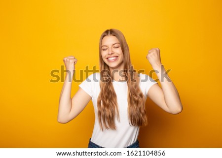 smiling blonde girl with closed eyes showing eyes gesture isolated on yellow