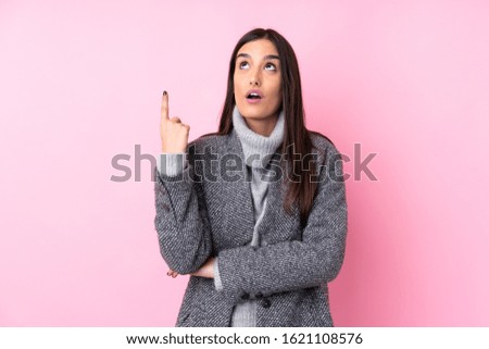 Young brunette woman over isolated pink background thinking an idea pointing the finger up
