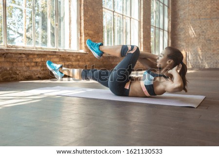 Sporty fit active young woman doing bicycle crunch situp exercise alone lying on mat wooden floor, strong sportswoman wear activewear training abs core muscles workout routine in sport gym studio Royalty-Free Stock Photo #1621130533