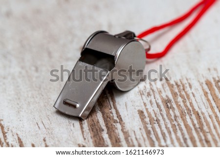 metal whistle on white wooden table, closeup photo