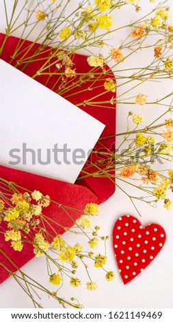 Open red envelope with a white leaf heart for inserting text on a white background sprigs of yellow flowers of different colors letter message congratulations on Valentine's day birthday wedding