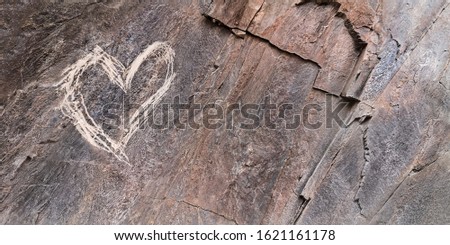 Heart roughly scratched on a rock. Rough glyptic.Declaration of love. Made with your own hands.The concept of impulsive expression of feelings and emotions. Valentines day brutal postcard design