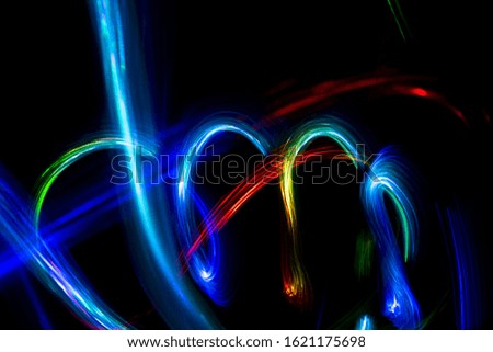 Abstract color pattern of luminous stripes on a black background, bright and smooth color streaks