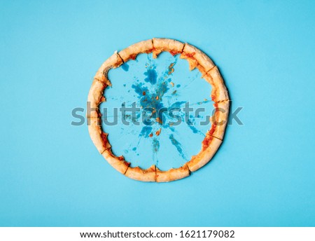 Pizza crust in a circle on blue background and grease traces. Flat lay of just pizza crust and crumbs. Eaten pizza context. Diet pizza funny concept. Royalty-Free Stock Photo #1621179082