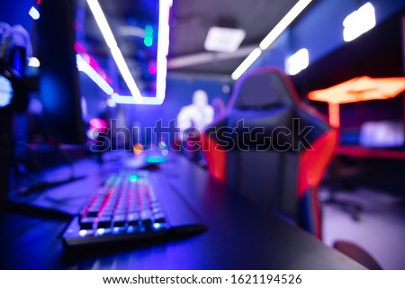 Blurred background professional gamer playing tournaments online games computer with headphones, red and blue.
