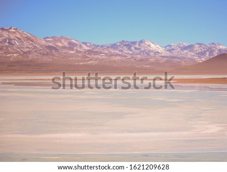 Snow-capped Mountain Range in Front of Blue Lake in A Rainbow of Colors Found in Bolivian Desert