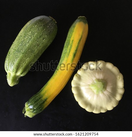 ORGANIC COURGETTES AND PATTY PAN SUMMER SQUASH,CUSTARD WHITE VARIETY ON BLACK BACKGROUND. Royalty-Free Stock Photo #1621209754