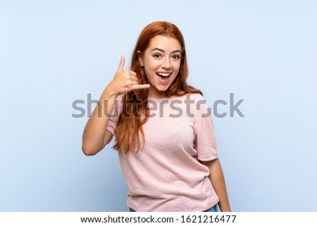 Teenager redhead girl over isolated blue background making phone gesture. Call me back sign