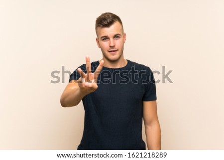 Young handsome blonde man over isolated background happy and counting three with fingers