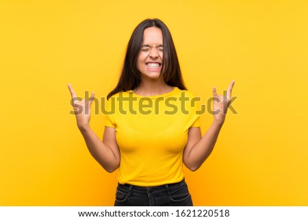 Young brunette girl over isolated background making rock gesture